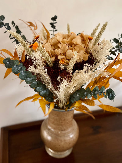 Le bouquet Cornaline est orné d'un hortensia et de fleurs séchées aux couleurs naturelles et orangées. 
