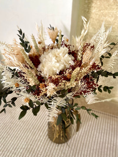 Un hortensia blanc avec du broom bloom marron, du parvifolia vert, le bouquet Émeraude, créé avec des fleurs séchées et stabilisées, est élégant. Aussi naturel et beau qu’un bouquet de fleurs fraîches, il pourra décorer votre table pour un dîner champêtre. 